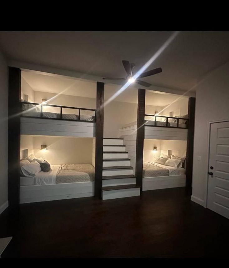 a room with bunk beds and stairs in the corner, all lit up by lights