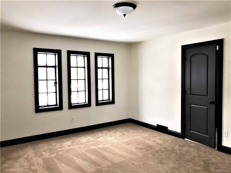 an empty room with three windows and a door in the center is shown here, there are no carpet on the floor