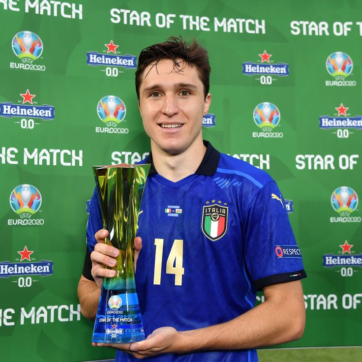 a young man holding up a trophy in front of a green wall with the words star of the match written on it