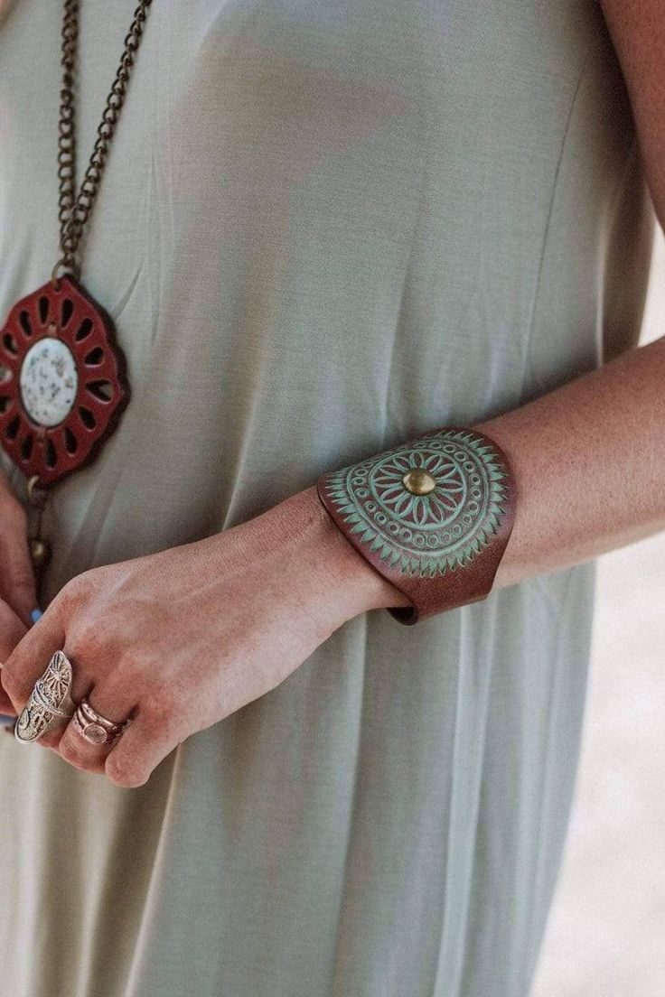 a woman is wearing a bracelet with an intricate design on it and holding onto her wrist