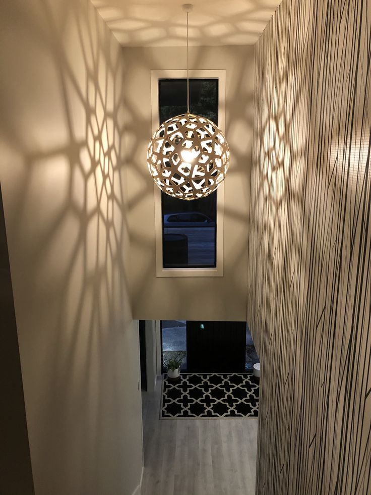 the light fixture is hanging from the ceiling in the hallway with shadows on the wall