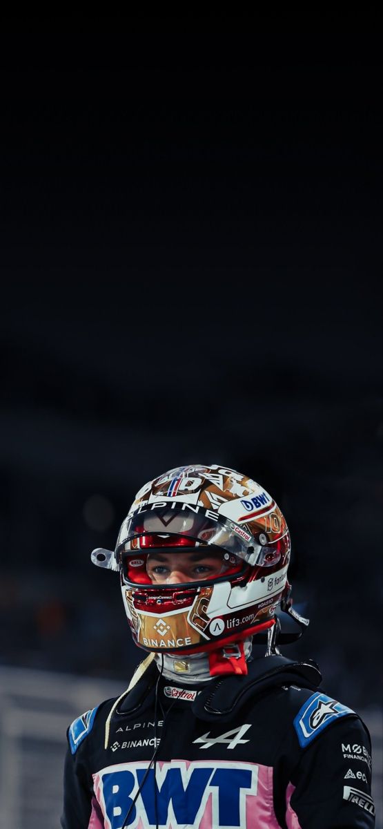 a person with a helmet on standing in front of a black background and looking off to the side