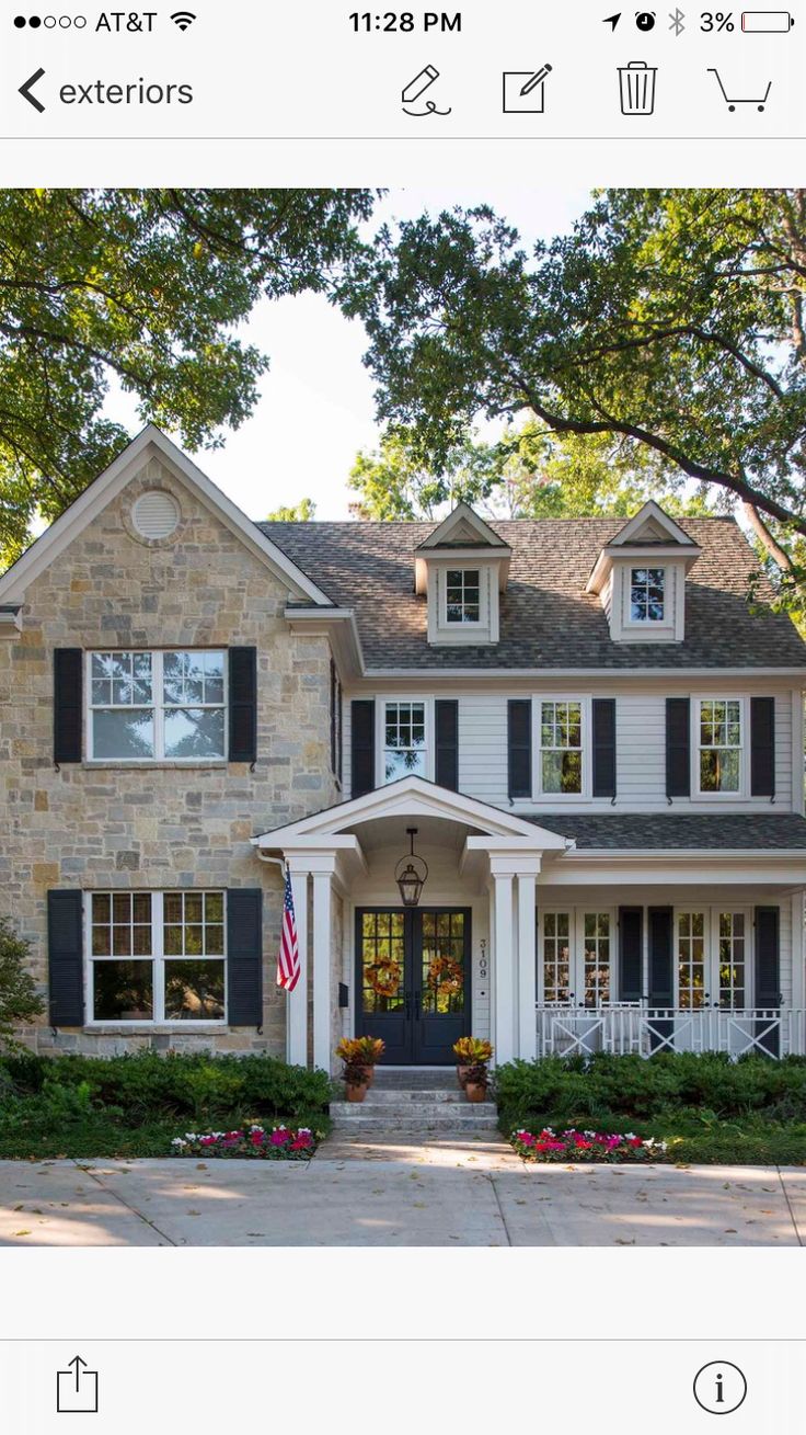 a large brick house with black shutters and white trim on the front door is shown