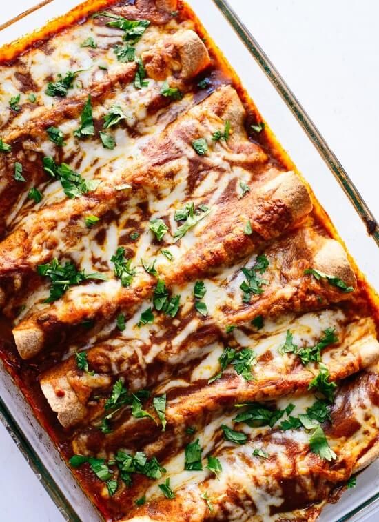 a casserole dish with meat, cheese and parsley in it on a white surface