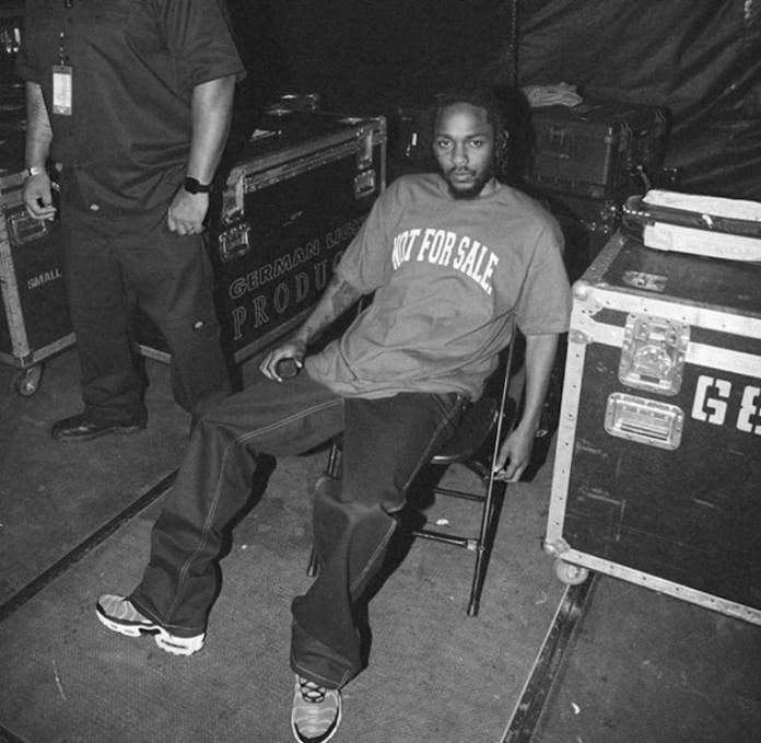 a man sitting on top of a chair in front of a guitar case and another person standing next to him