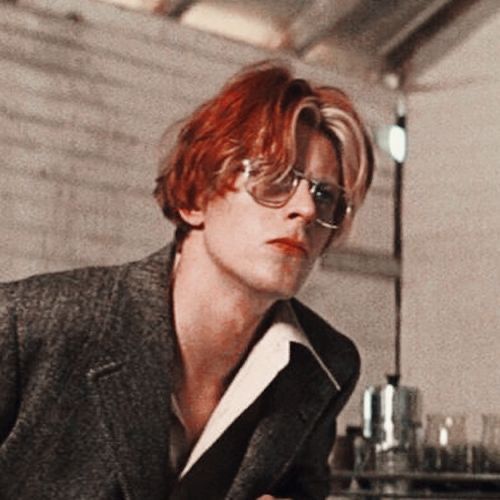 a man with red hair and glasses in a room