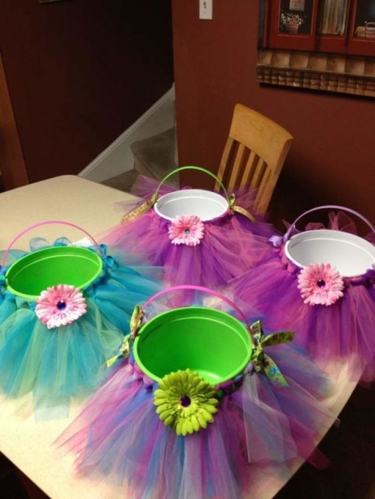 three buckets are sitting on top of a table with colorful tulle skirts around them