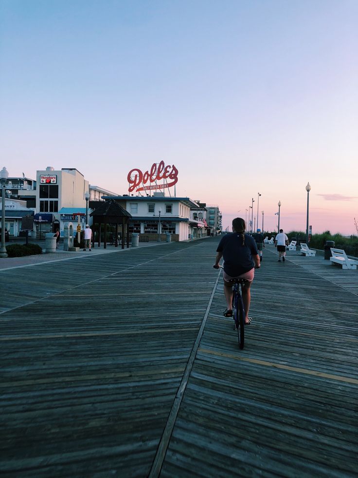 a man riding a bike down a wooden boardwalk next to a building with a sign on it