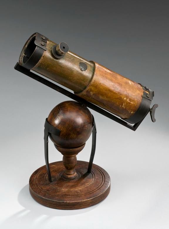 an old telescope is sitting on top of a wooden stand with a metal object attached to it