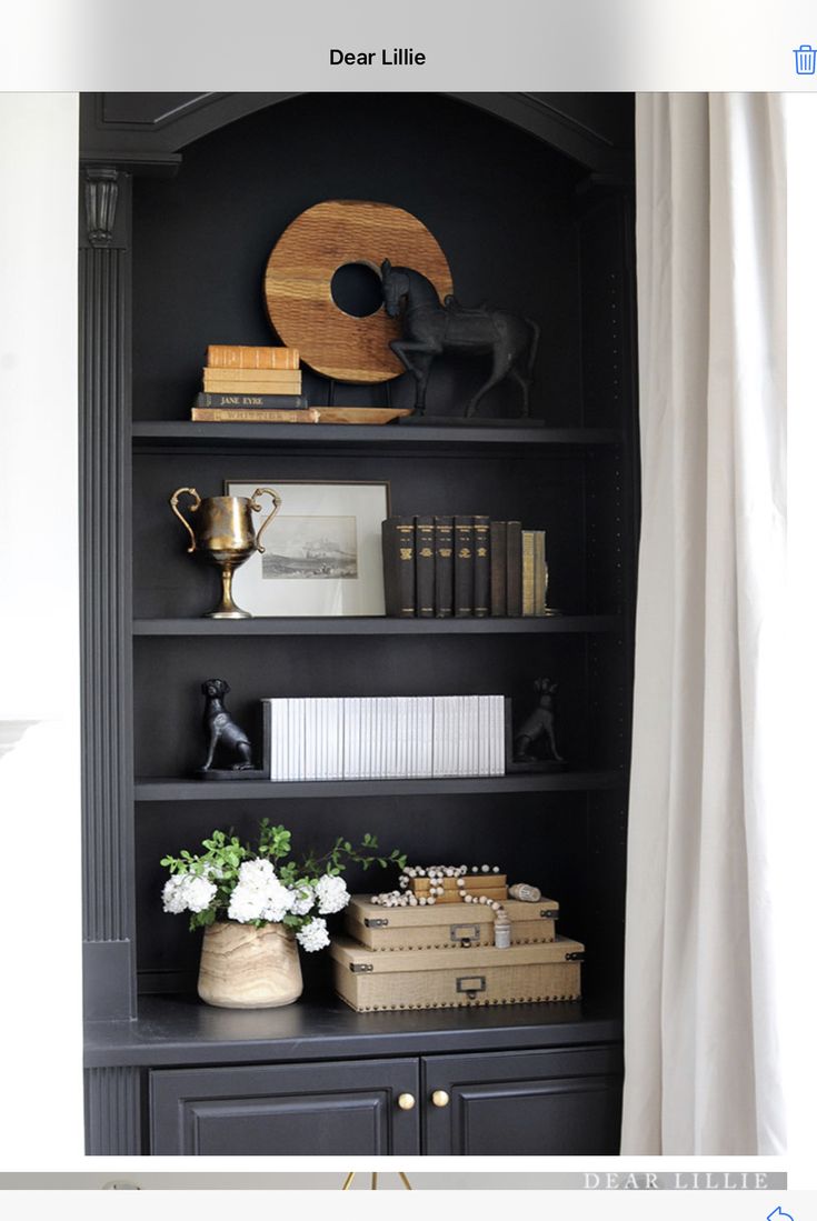 a black bookcase with books, vases and other items on top of it