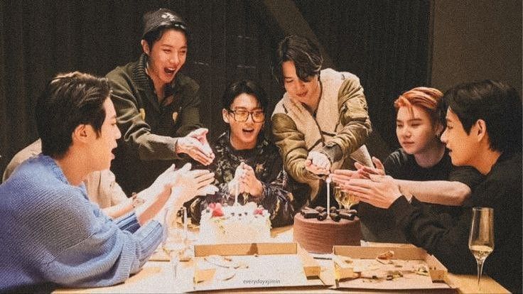 a group of people sitting around a table eating cake