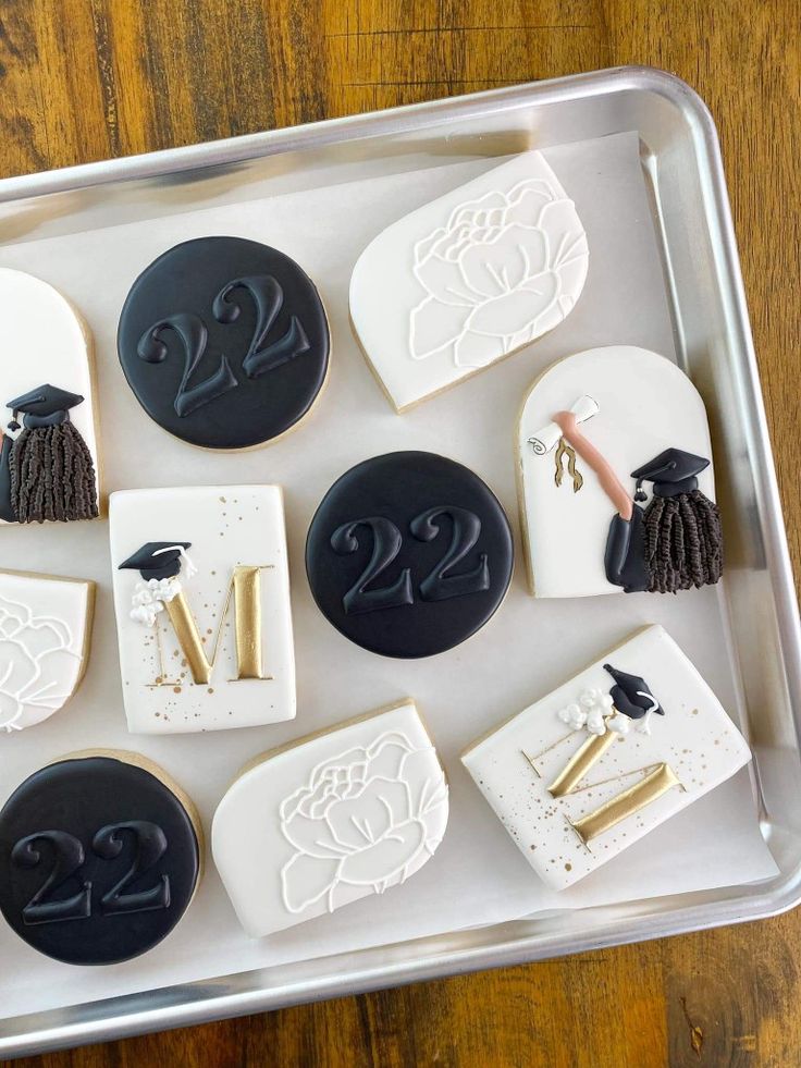 decorated cookies in the shape of graduation caps and tassels on a baking sheet