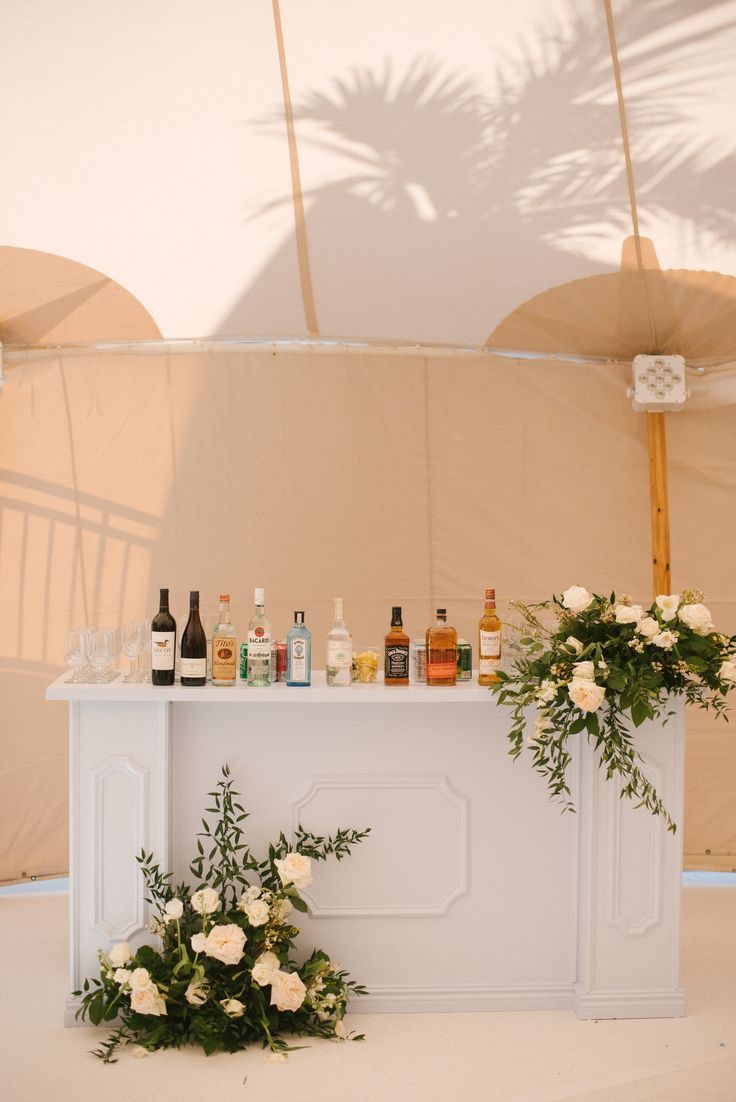 an outdoor bar with flowers and bottles on it