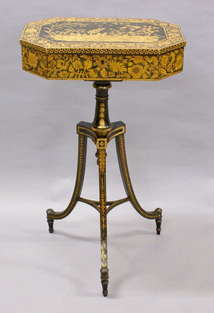 an ornately decorated wooden table with gold and black paint on the top, sitting against a white background