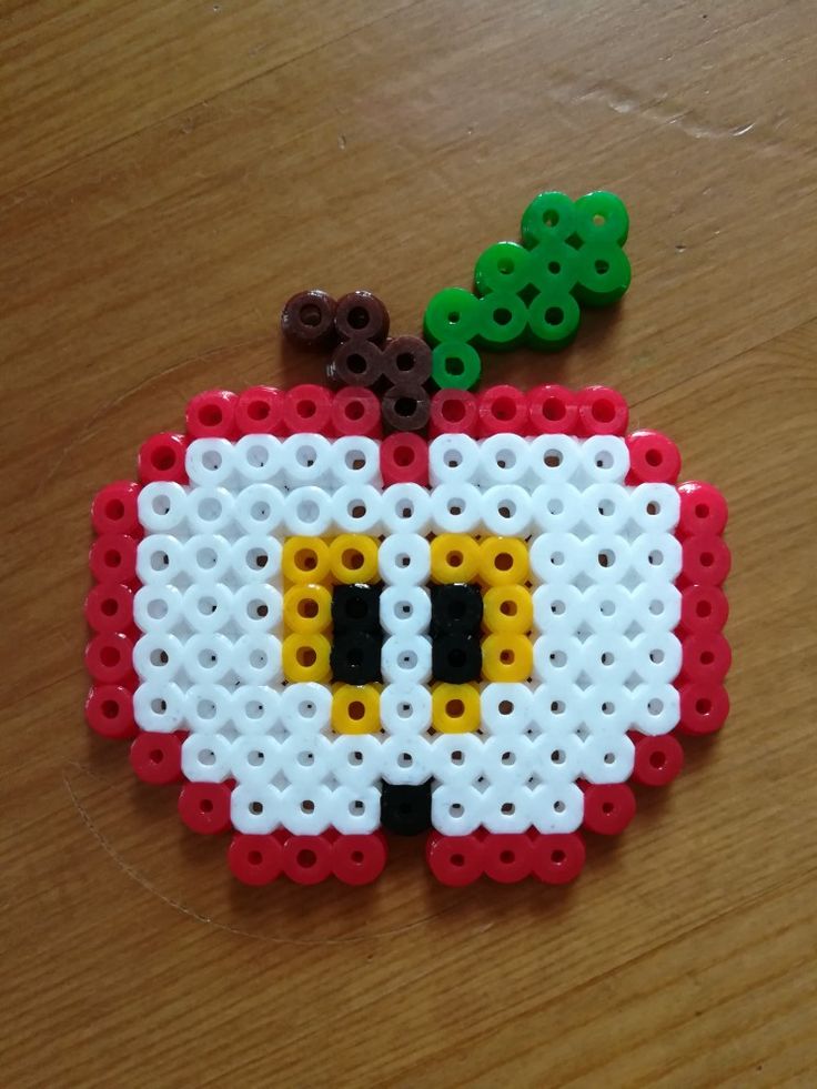 an apple made out of legos sitting on top of a wooden table next to two green and brown beads