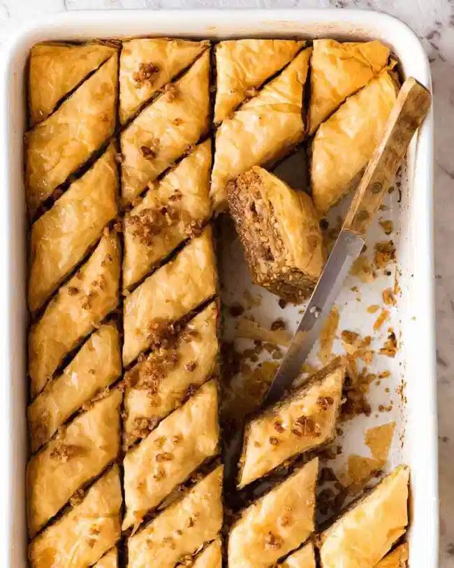 a white dish filled with pastries next to a knife