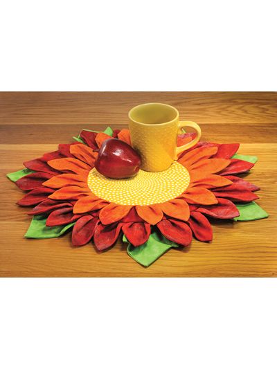 a sunflower shaped placemat with a coffee cup on it and an apple in the middle