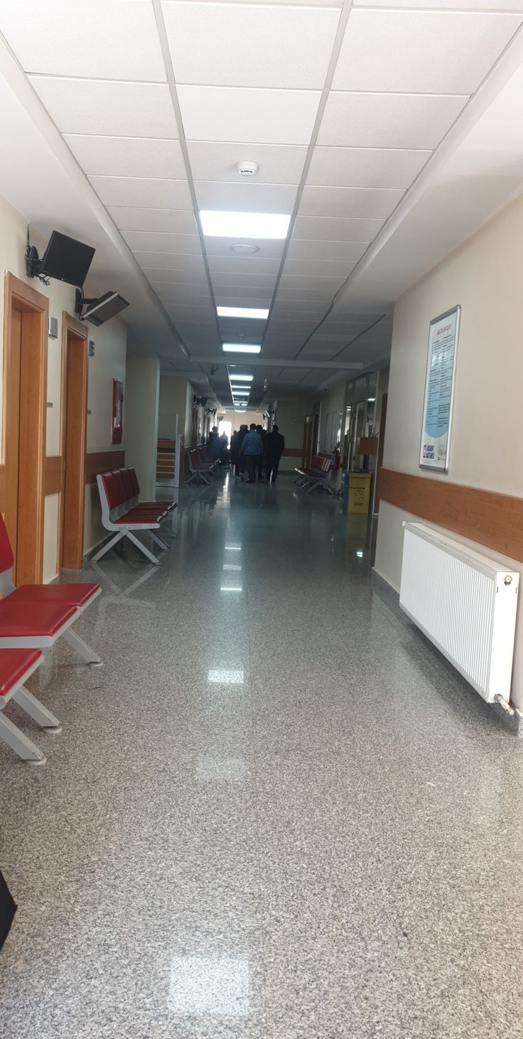 an empty hallway with red chairs and white walls