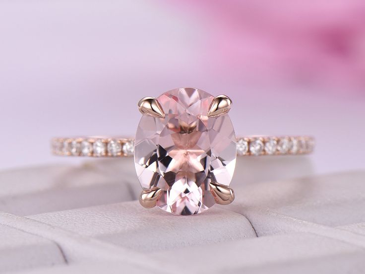 a pink diamond ring sitting on top of a white box