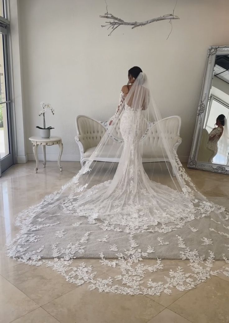 a woman in a wedding dress is standing near a mirror