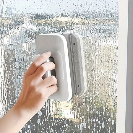 a person is holding an electronic device in front of a window with rain drops on it