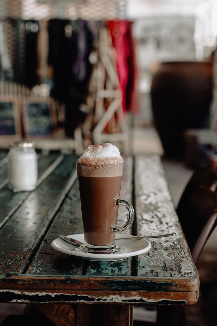 a cup of coffee sitting on top of a wooden table