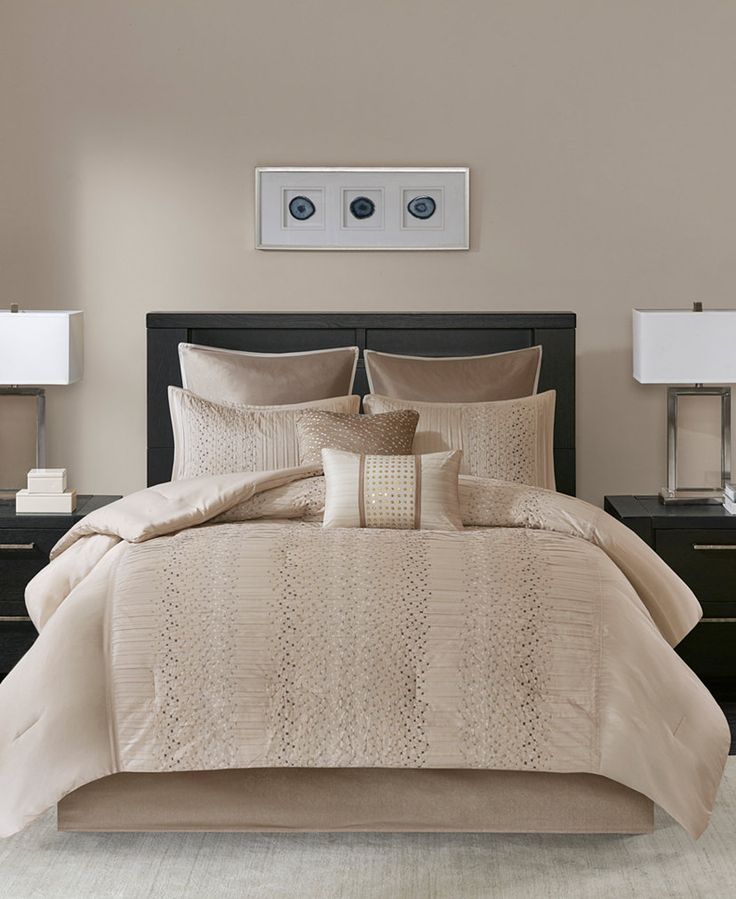 a bed with beige comforter and pillows in a room next to two nightstands