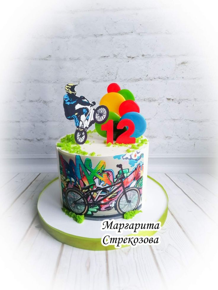 a birthday cake decorated with colorful balloons and a bike on the top that reads 12