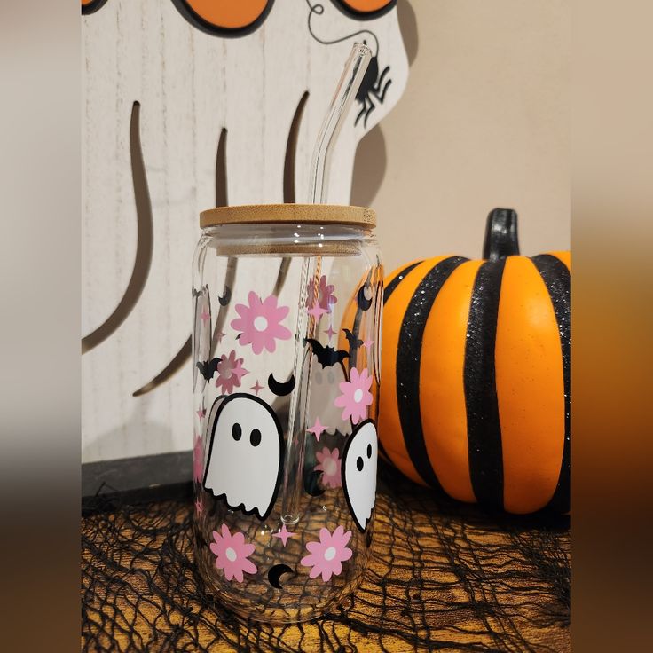 two decorated mason jars sitting on top of a table next to a pumpkin and spider