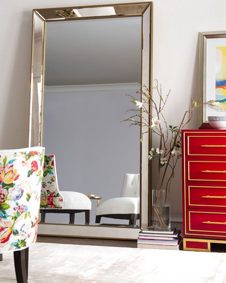 a large mirror sitting on top of a dresser next to a red chest of drawers