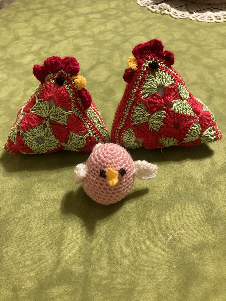 two crocheted birds sitting next to each other on a bed