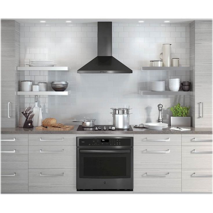 a stove top oven sitting inside of a kitchen next to white cupboards and shelves