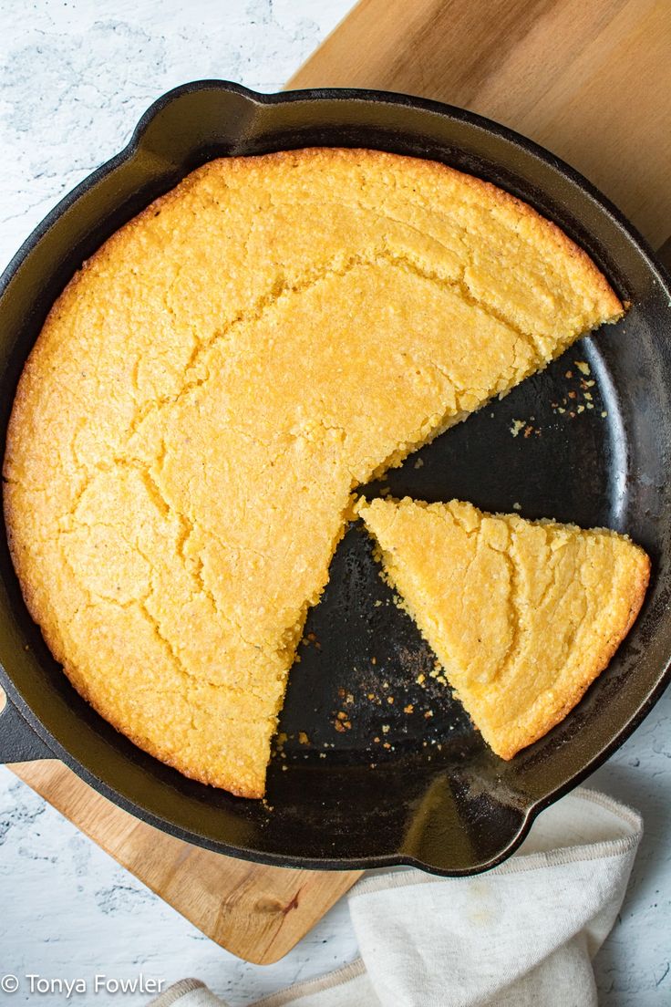 a skillet with a cake in it on a wooden cutting board