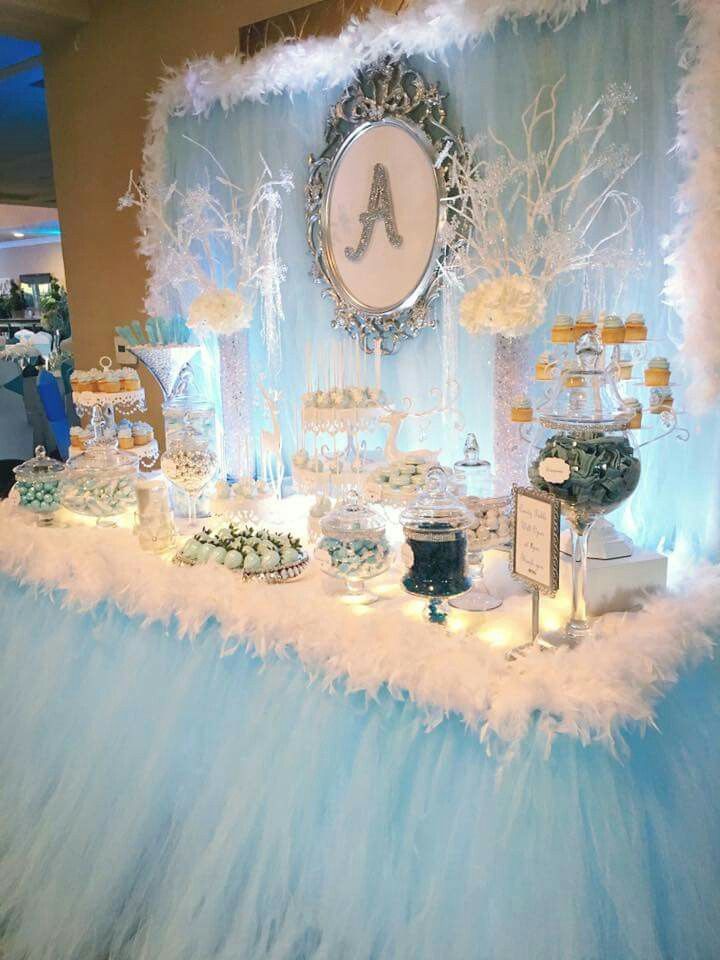 a blue and white dessert table at a baby's first birthday party with feathers on it