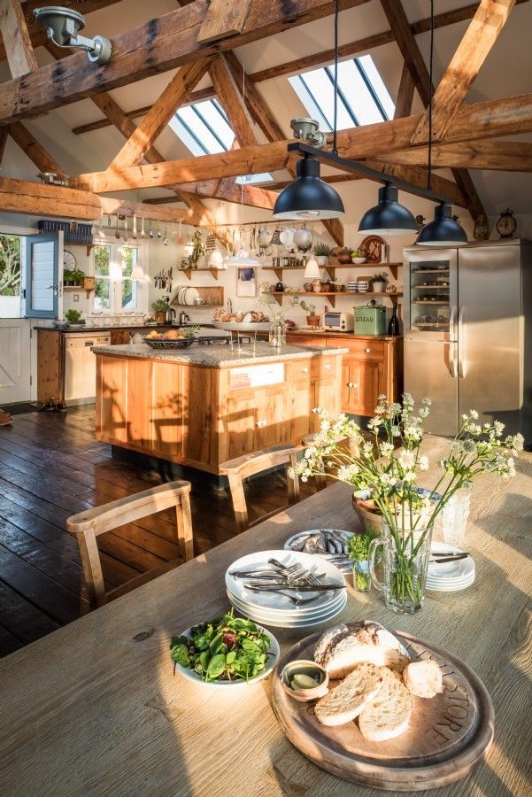 an open kitchen and dining area with wooden beams on the ceiling, along with plates of food