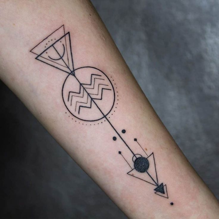 a black and white photo of a tattoo with an arrow in the center on someone's arm