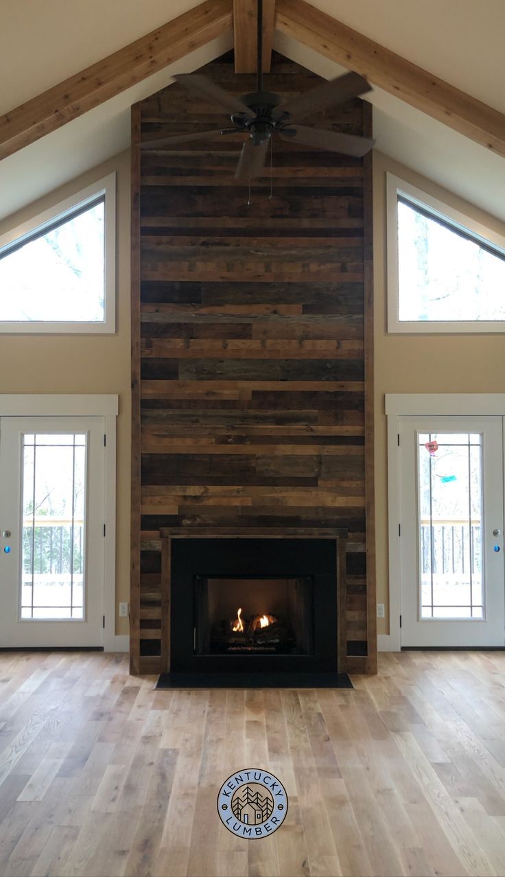 a living room with wood paneling and a fire place in the middle of it