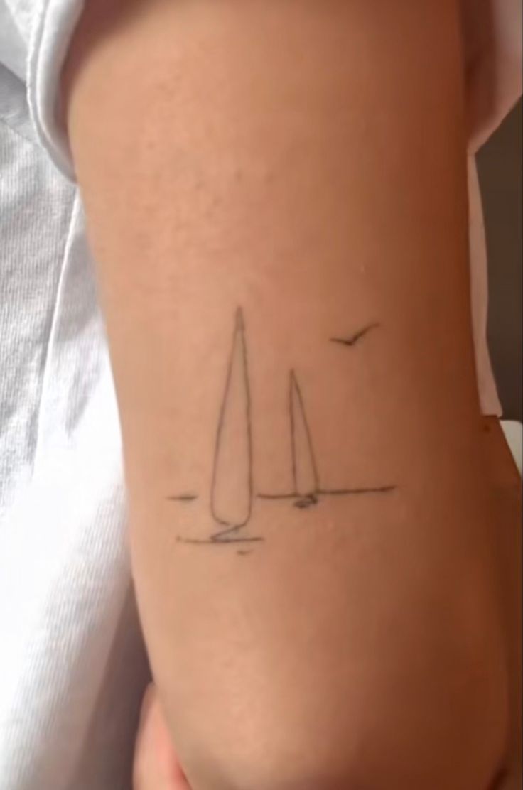 a person with a small sailboat tattoo on their back side ribcading it