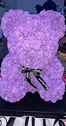 a purple teddy bear made out of flowers sitting on a black table with other items in the background