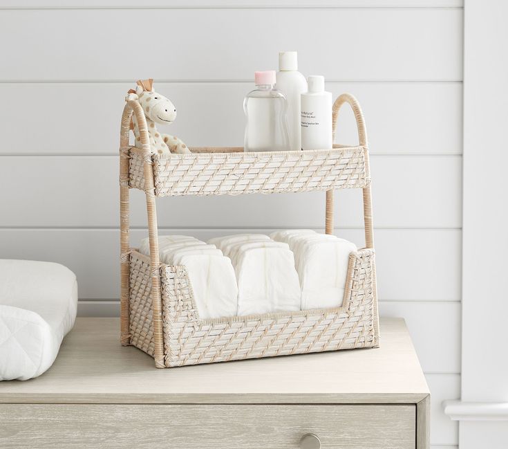 a wicker shelf with towels and soaps on it next to a white wall