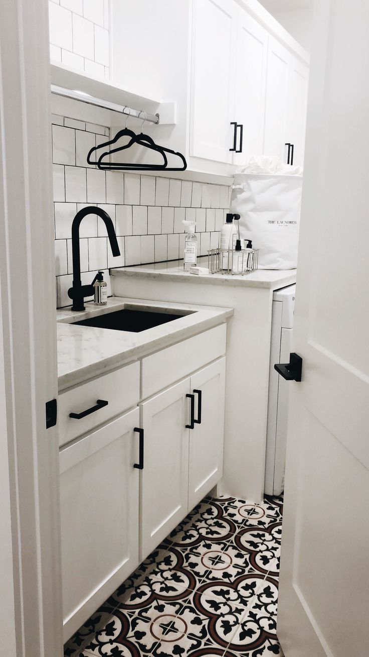 a kitchen with black and white tile flooring next to a sink, stove top oven and dishwasher