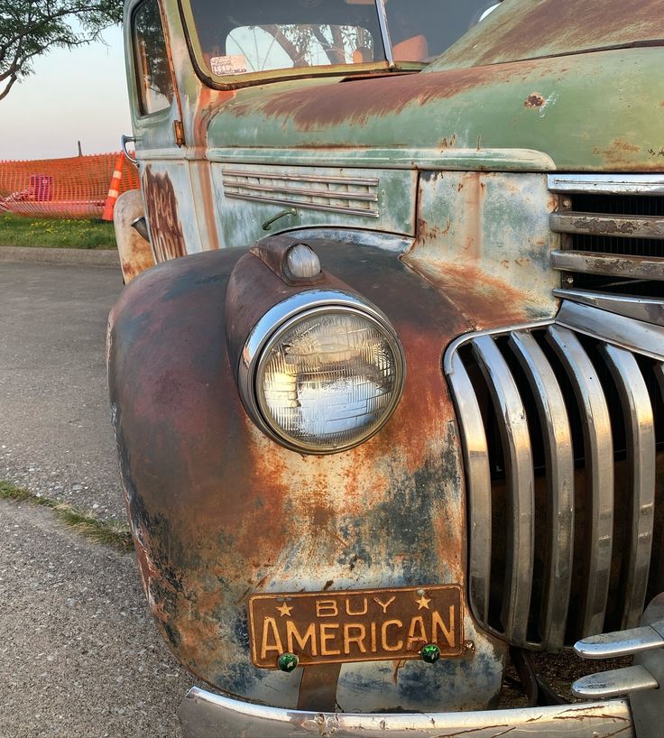 an old rusted truck is parked on the side of the road with its license plate