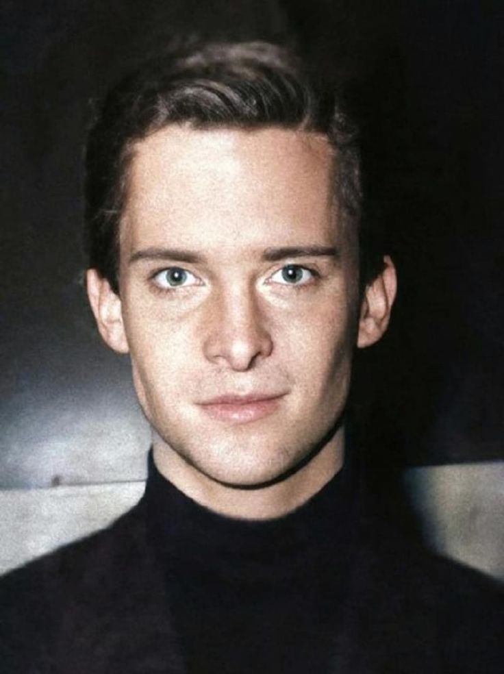 a close up of a person wearing a black turtle neck shirt and looking at the camera