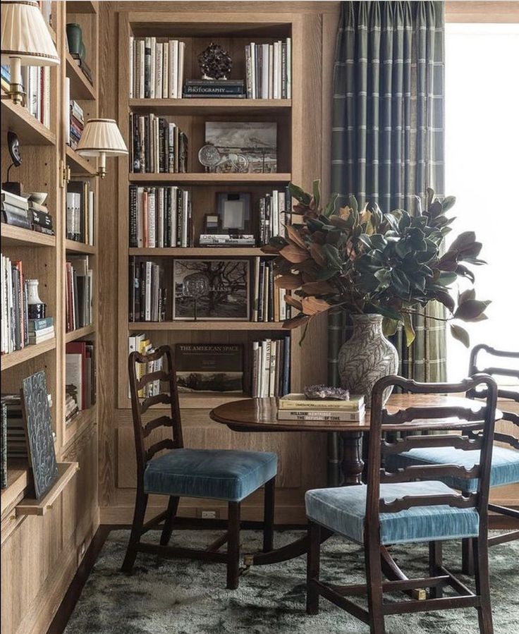 a dining room table with two chairs and bookshelves