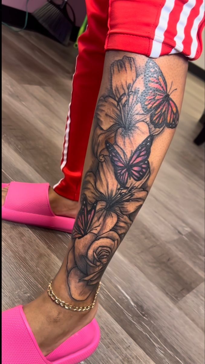 a woman's leg with flowers and butterflies on it, while she is wearing pink shoes