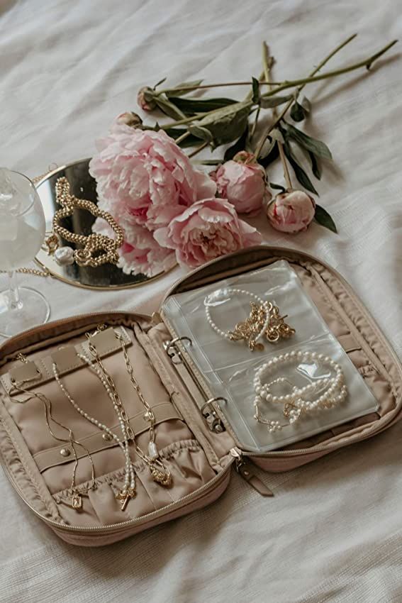 an open suitcase on a bed with jewelry in it and flowers next to the bag