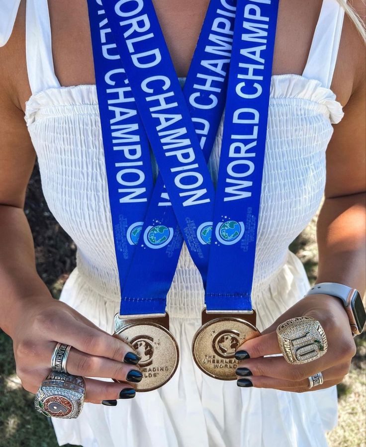 a woman holding two gold and silver medals in her hands, with the words world champion written on them