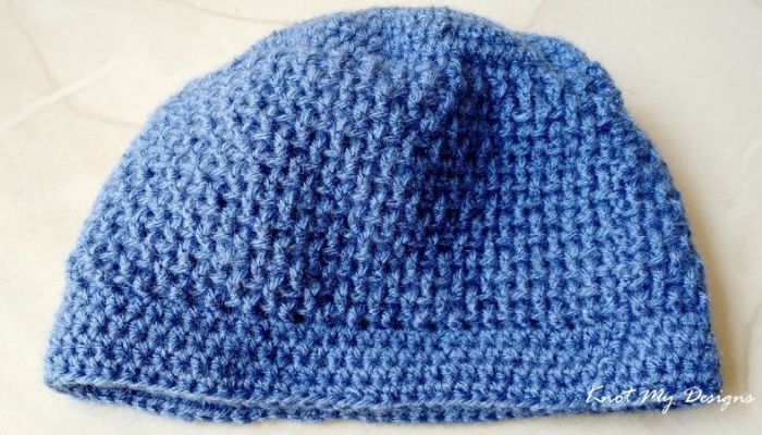 a crocheted blue hat sitting on top of a table