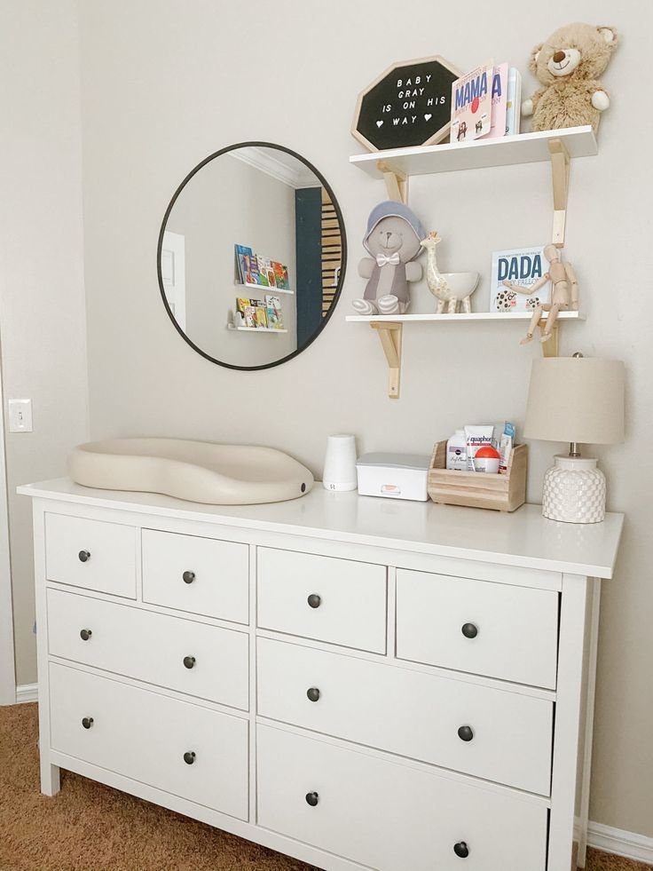 a baby's room with white dressers and toys on top of the dresser