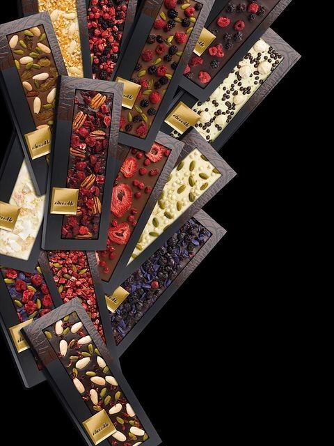 an assortment of chocolates, nuts and dried berries arranged in rows on a black background